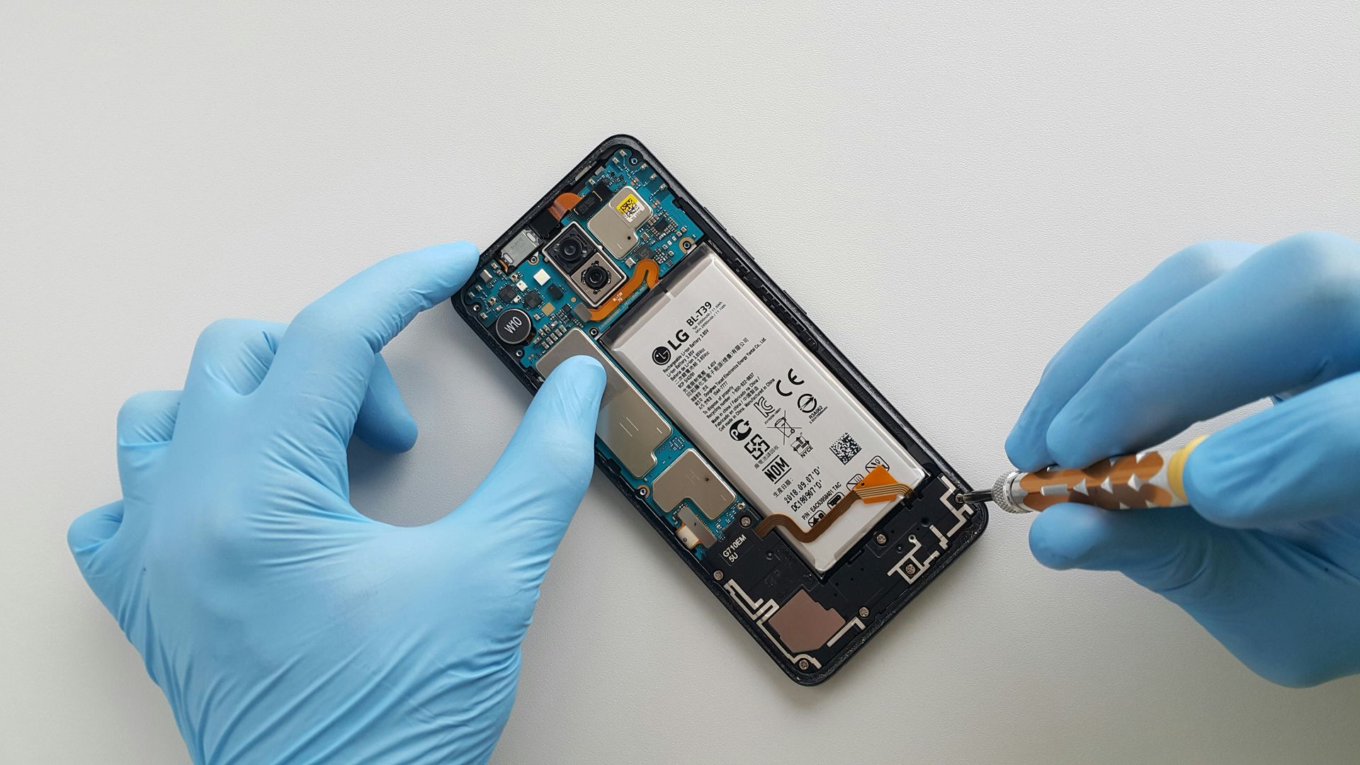 a person in blue gloves is removing a cell phone